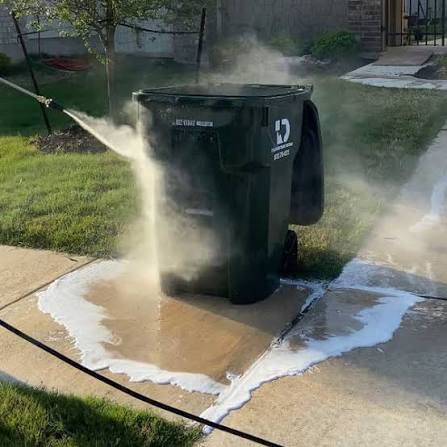 Pressure washing a curbside trash bin with foam and spray
